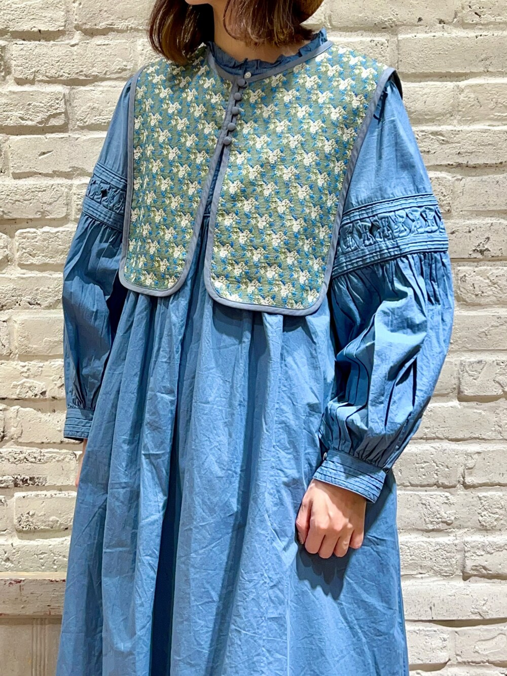 ブルー系のベスト、ブルー系のワンピース、ホワイト系のスカートを着用したレディースの春コーディネートの2枚目の写真