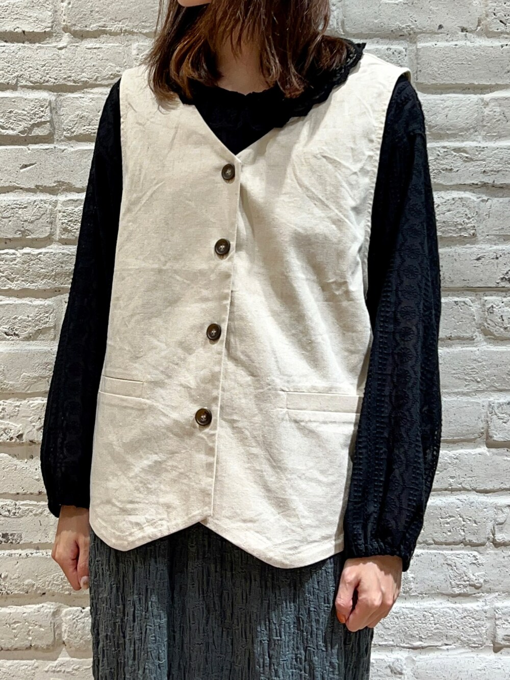 ブラック系のシャツ/ブラウス、ホワイト系のベスト、ブラック系のハンドバッグを着用したレディースの秋コーディネートの2枚目の写真