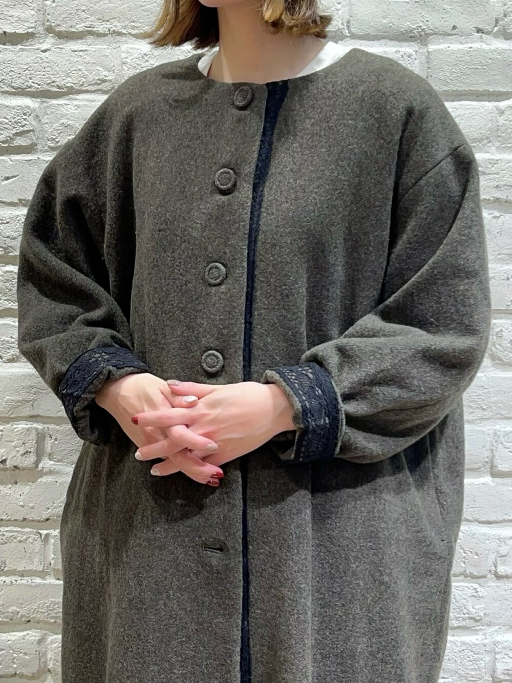 グリーン系のノーカラーコート、ホワイト系のシャツ/ブラウス、ブラウン系のその他パンツを着用したレディースの冬コーディネートの2枚目の写真