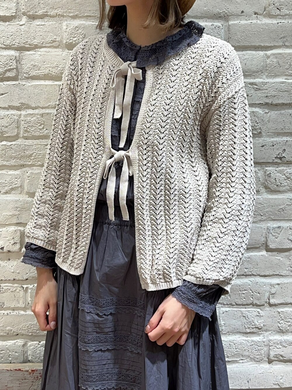 ホワイト系のカーディガン/ボレロ、グレー系のシャツ/ブラウス、グレー系のスカートを着用したレディースの春コーディネートの2枚目の写真