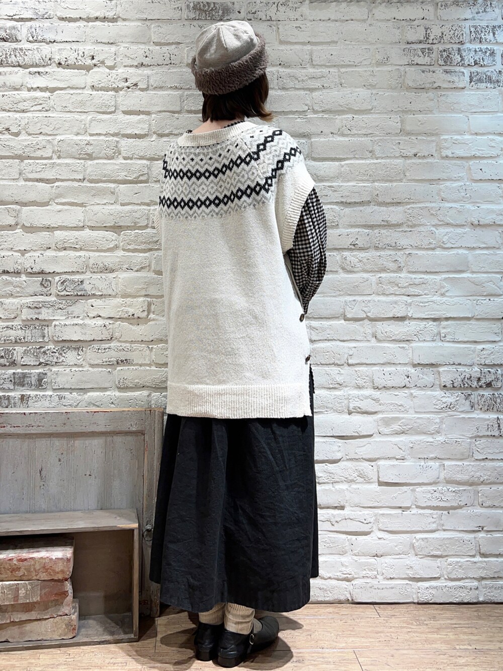 ホワイト系のベスト、ブラック系のチュニック、ブラック系のスカートを着用したレディースの冬コーディネートの5枚目の写真