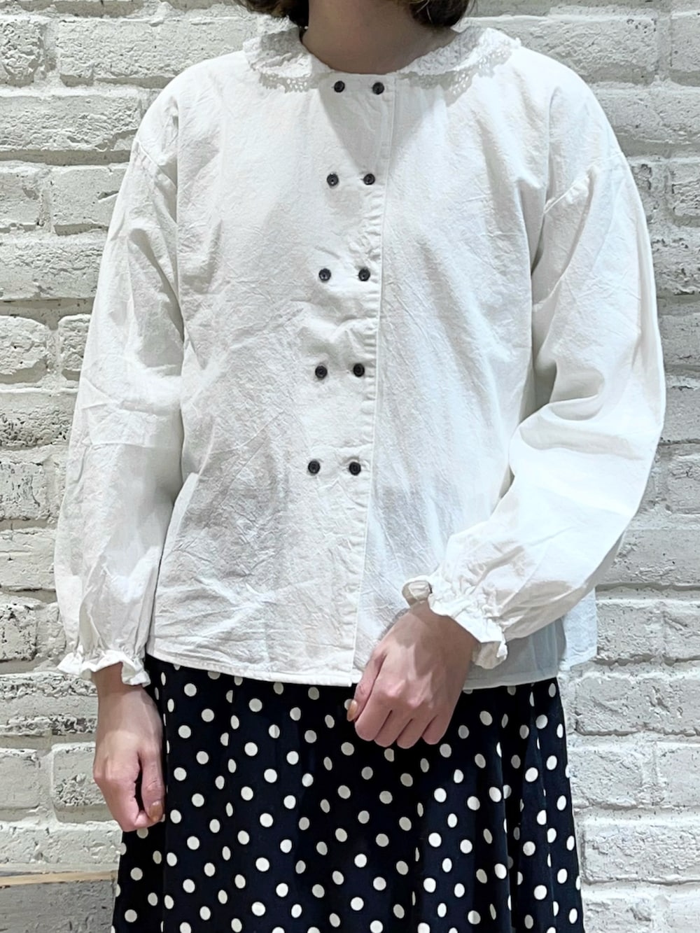 ベージュ系のニット/セーター、ホワイト系のシャツ/ブラウス、ブラック系のスカートを着用したレディースの冬コーディネートの3枚目の写真