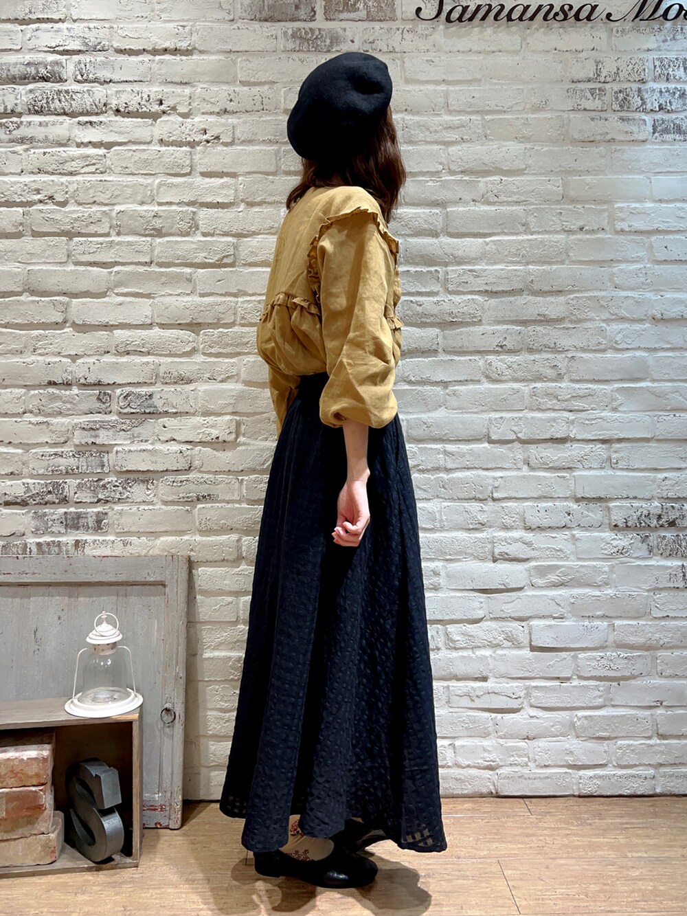 イエロー系のチュニック、ブラック系のスカート、ブラック系のハットを着用したレディースの秋コーディネートの3枚目の写真