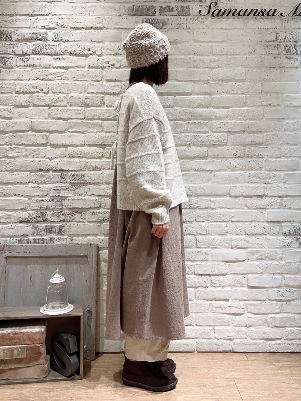 ホワイト系のカーディガン/ボレロ、ブラウン系のワンピース、ベージュ系のカーゴパンツを着用したレディースの冬コーディネートの3枚目の写真