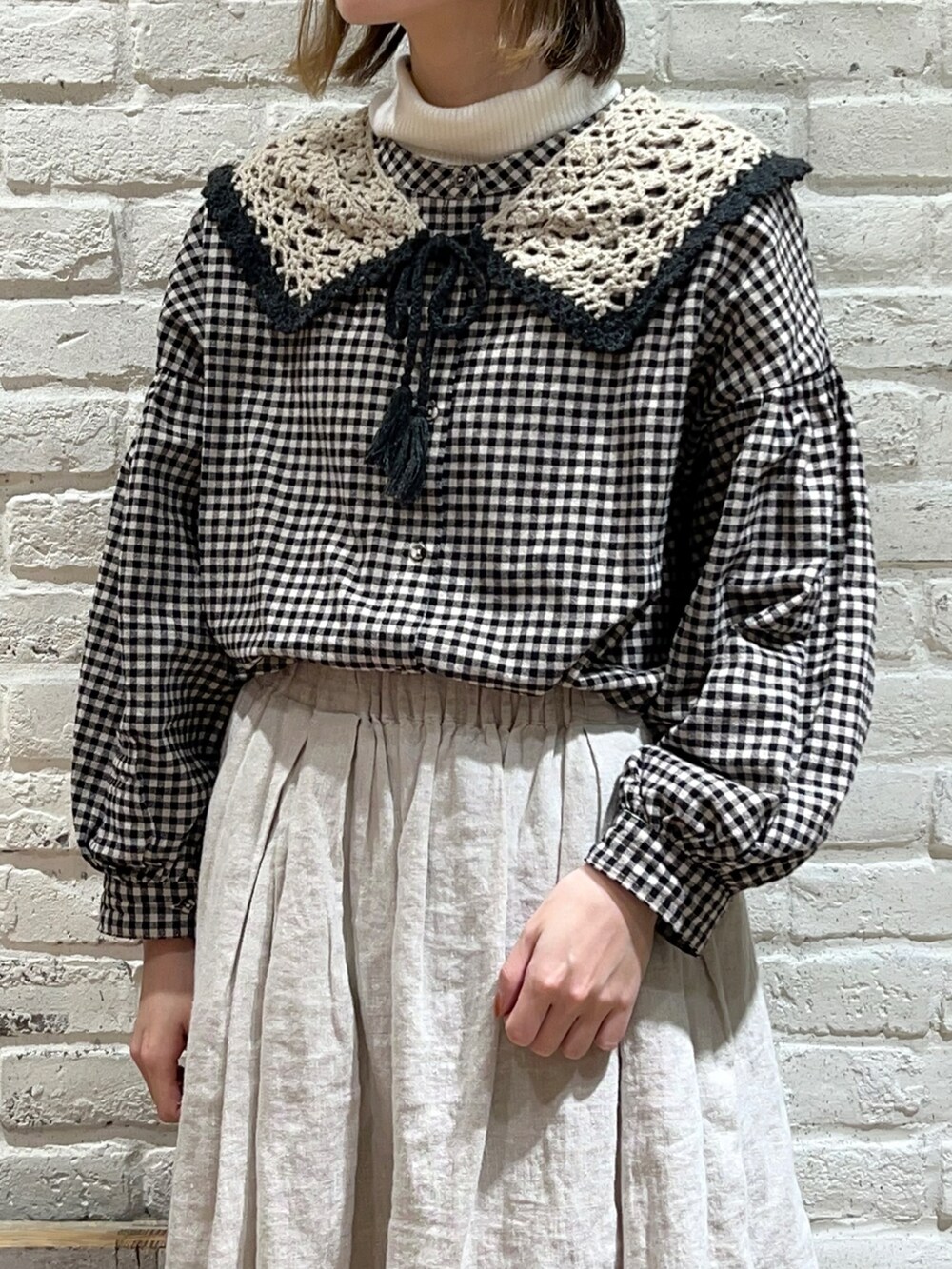 ホワイト系のニット/セーター、ブラック系のチュニック、ホワイト系のスカートを着用したレディースの冬コーディネートの2枚目の写真