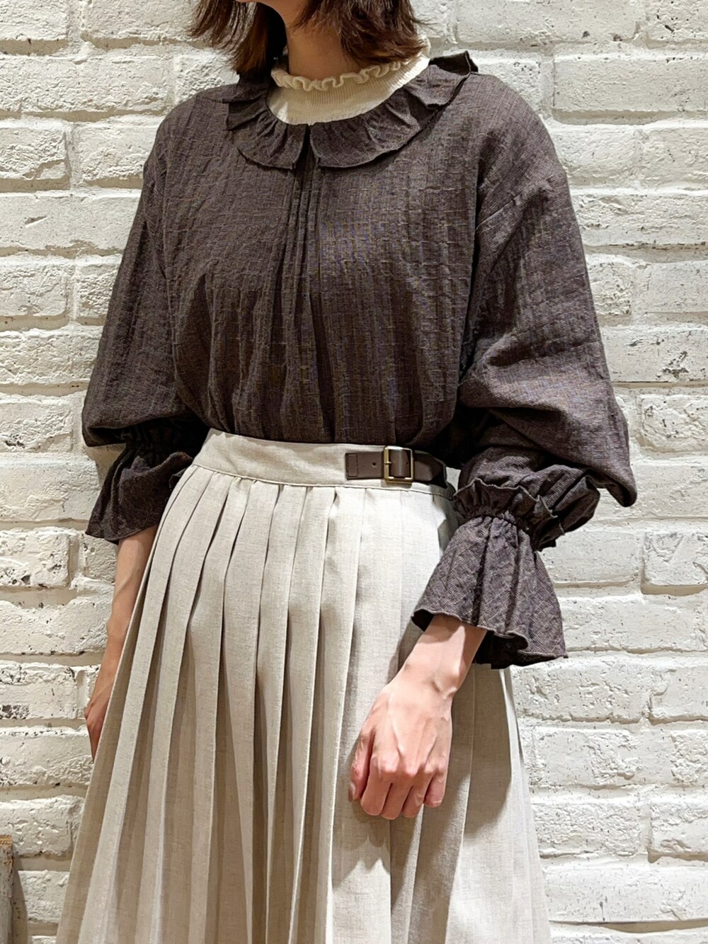 ホワイト系のニット/セーター、グレー系のシャツ/ブラウス、ベージュ系のカーディガン/ボレロを着用したレディースの冬コーディネートの3枚目の写真