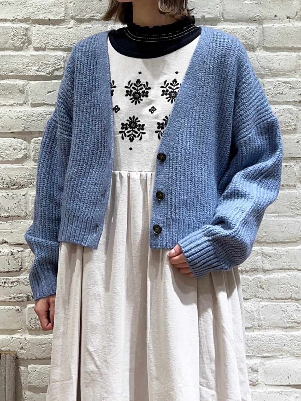 ブラック系のニット/セーター、ホワイト系のワンピース、ブルー系のカーディガン/ボレロを着用したレディースの冬コーディネートの2枚目の写真