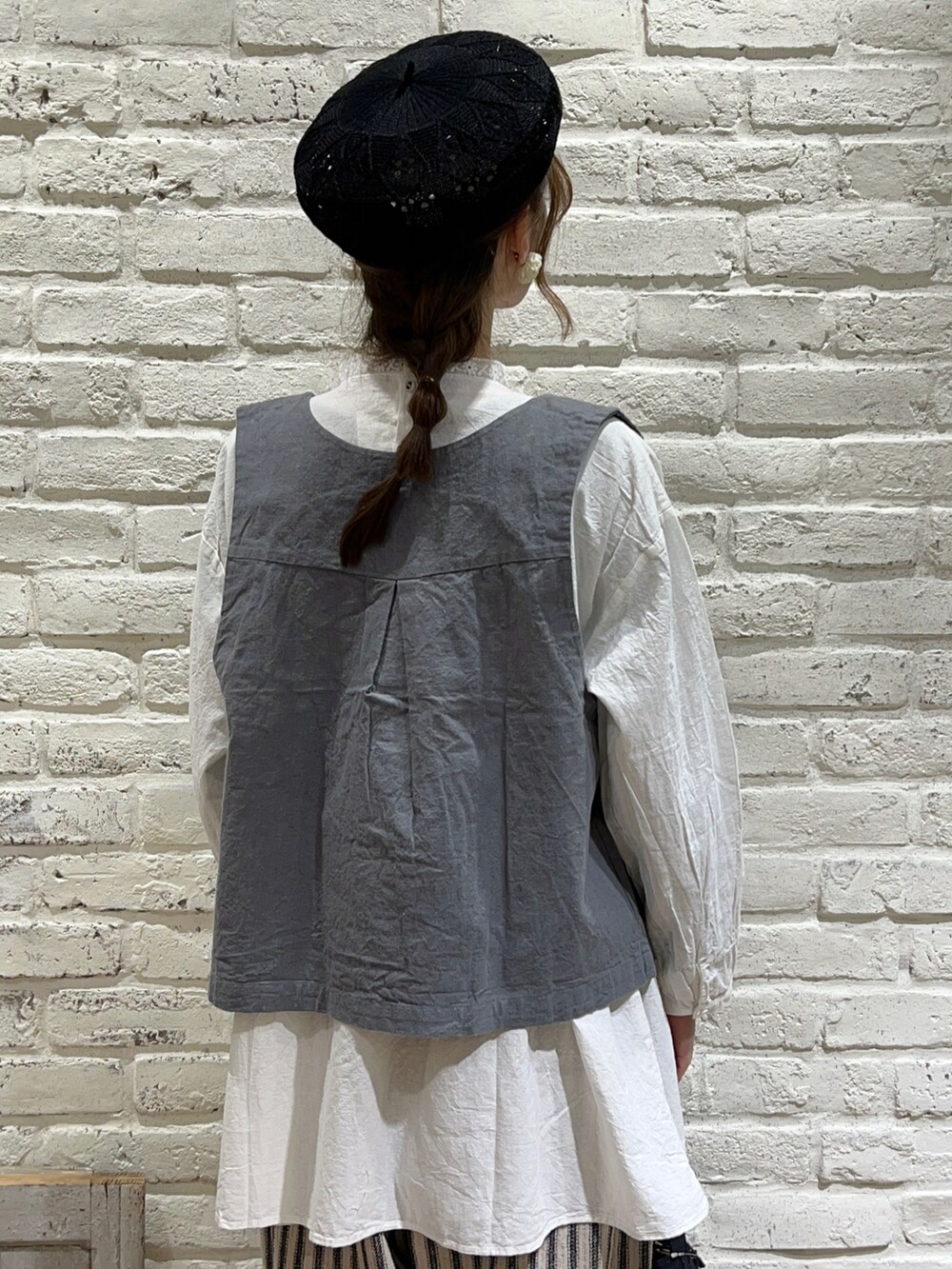 グリーン系のベスト、ホワイト系のシャツ/ブラウス、ブラック系のかごバッグを着用したレディースの春コーディネートの5枚目の写真