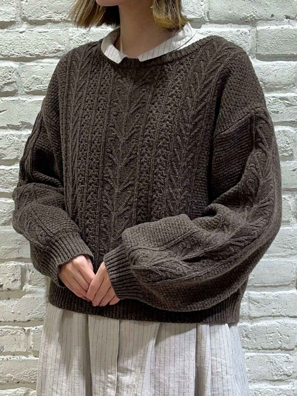 ブラウン系のカーディガン/ボレロ、ベージュ系のワンピース、ブラック系のスカートを着用したレディースの秋コーディネートの2枚目の写真