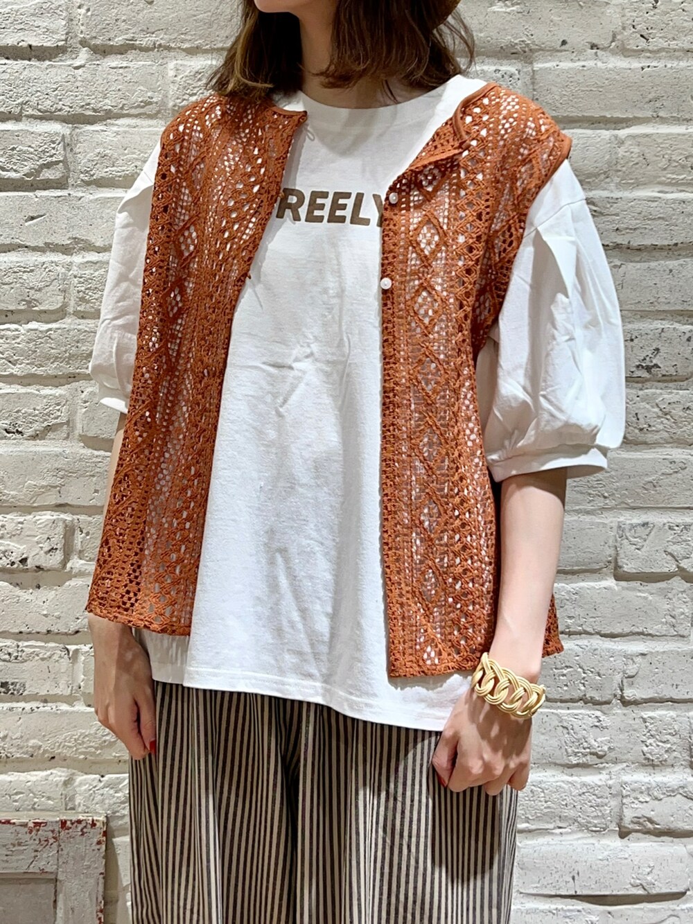 オレンジ系のTシャツ/カットソー、ホワイト系のハンドバッグ、ベージュ系のその他パンツを着用したレディースの秋コーディネートの2枚目の写真