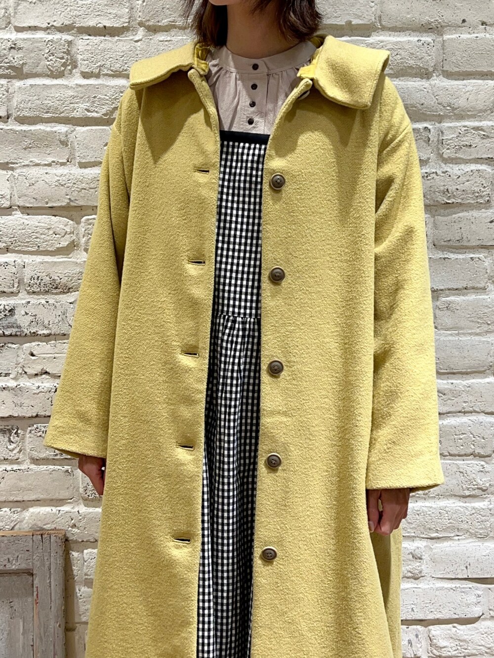 ベージュ系のチュニック、イエロー系のその他アウター、ホワイト系のブーツを着用したレディースの冬コーディネートの2枚目の写真