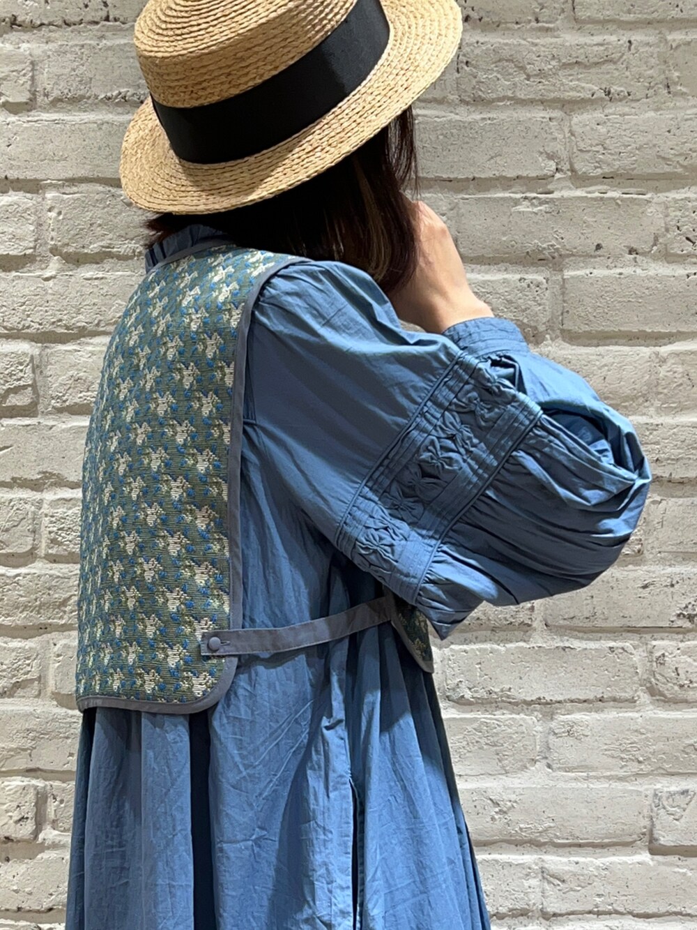 ブルー系のベスト、ブルー系のワンピース、ホワイト系のスカートを着用したレディースの春コーディネートの4枚目の写真