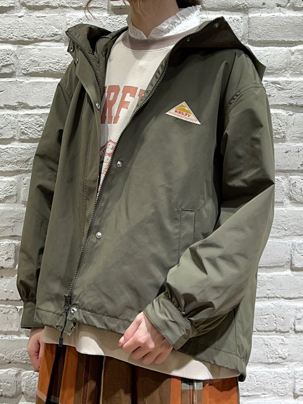ホワイト系のシャツ/ブラウス、グリーン系のマウンテンパーカー、ホワイト系のTシャツ/カットソーを着用したレディースの秋コーディネートの2枚目の写真