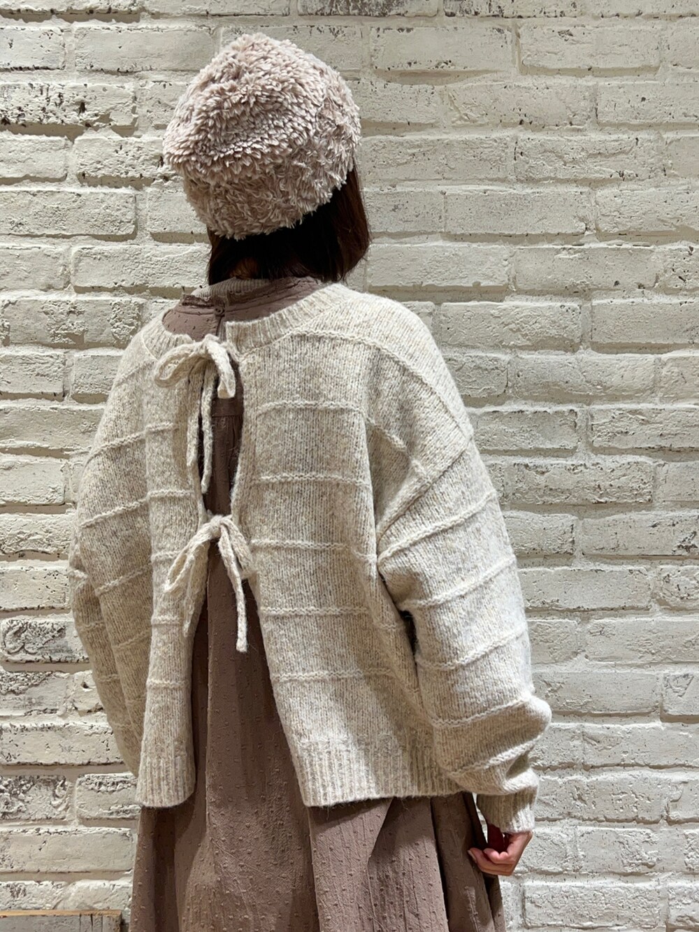 ホワイト系のカーディガン/ボレロ、ブラウン系のワンピース、ベージュ系のカーゴパンツを着用したレディースの冬コーディネートの2枚目の写真