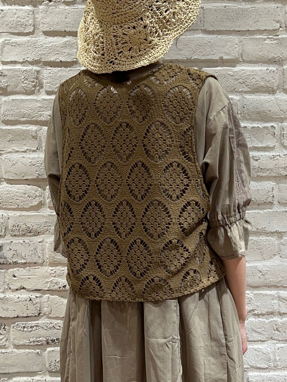 グリーン系のベスト、グリーン系のワンピース、ホワイト系のスカートを着用したレディースの秋コーディネートの4枚目の写真