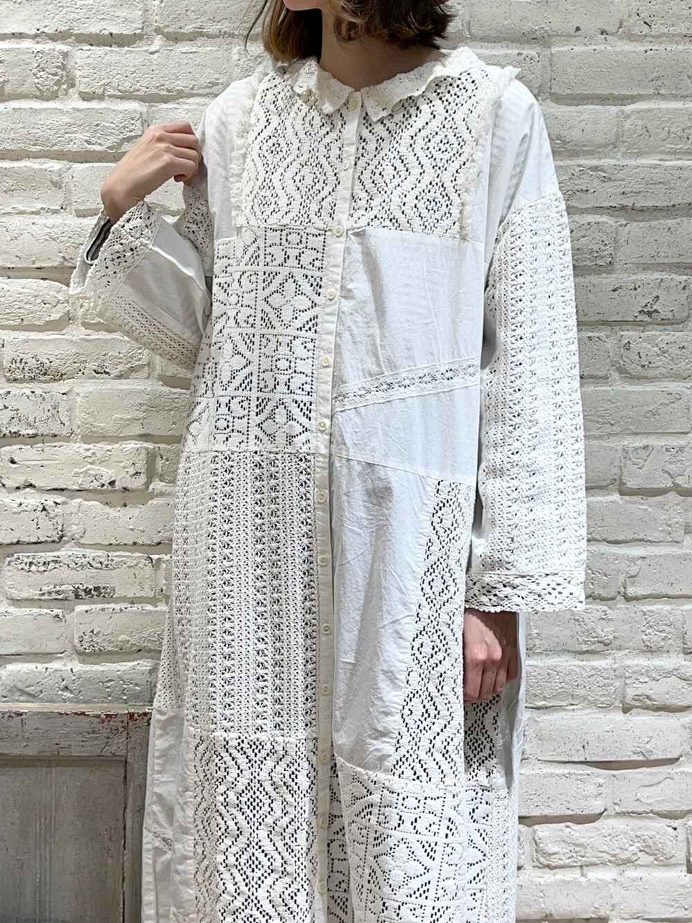 ブラウン系のニット/セーター、ホワイト系のワンピース、ブルー系のデニムパンツを着用したレディースの春コーディネートの3枚目の写真