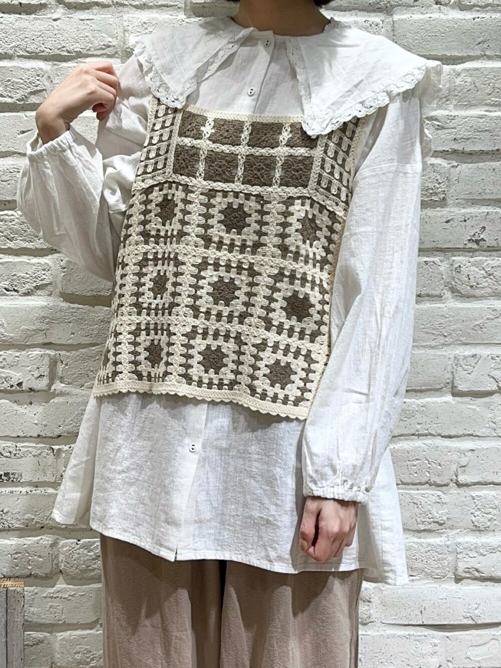 ホワイト系のチュニック、ホワイト系のベスト、ベージュ系のショルダーバッグを着用したレディースの秋コーディネートの2枚目の写真