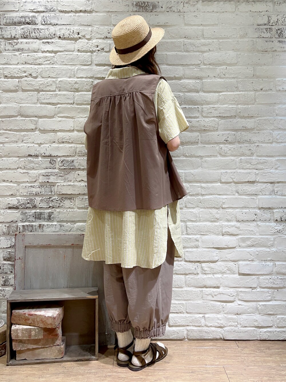 ホワイト系のタンクトップ、ブラウン系のベスト、イエロー系のチュニックを着用したレディースの夏コーディネートの4枚目の写真