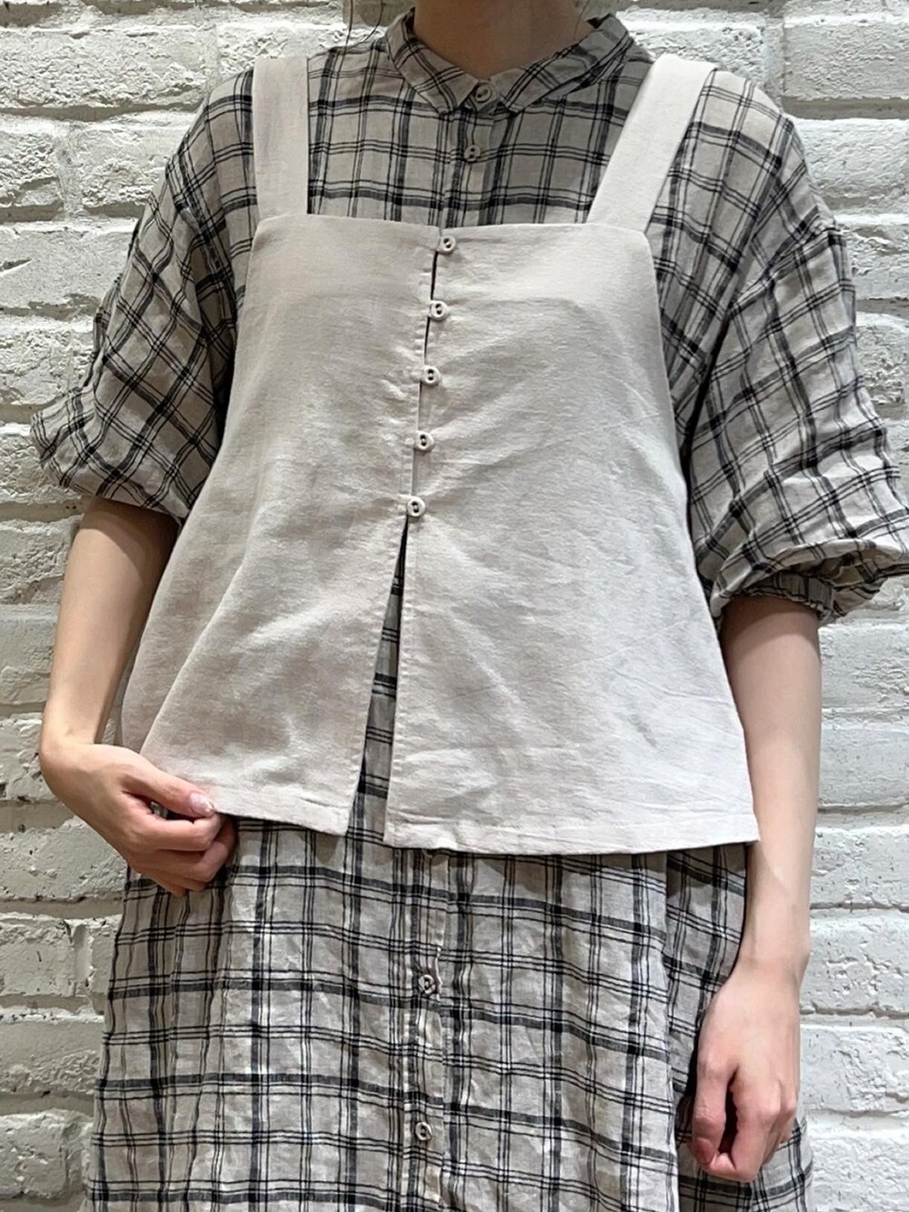 ベージュ系のベスト、ホワイト系のワンピース、ブラック系のスカートを着用したレディースの夏コーディネートの2枚目の写真