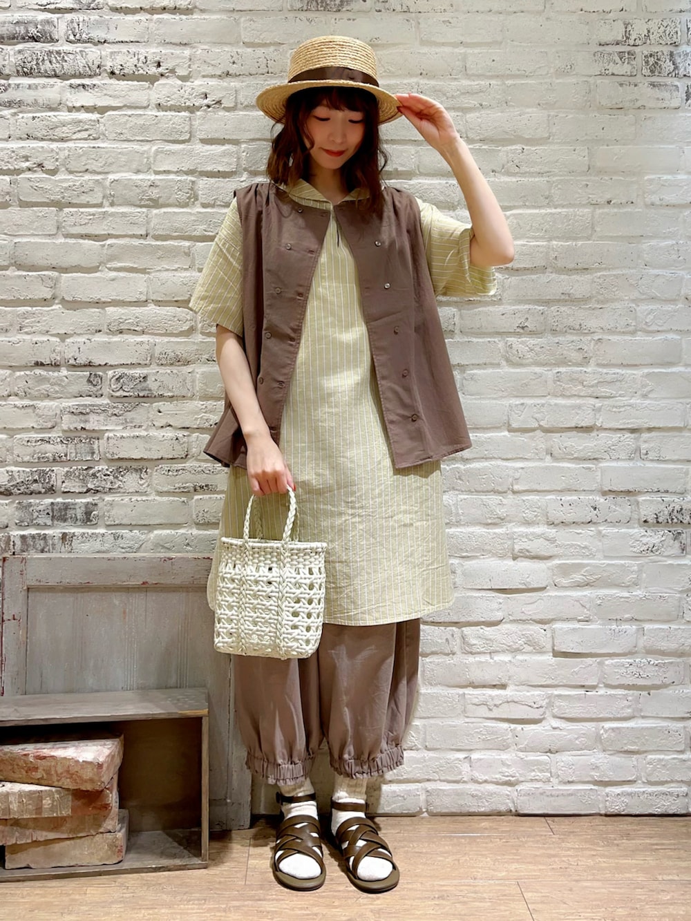 ホワイト系のタンクトップ、ブラウン系のベスト、イエロー系のチュニックを着用したレディースの夏コーディネートの2枚目の写真