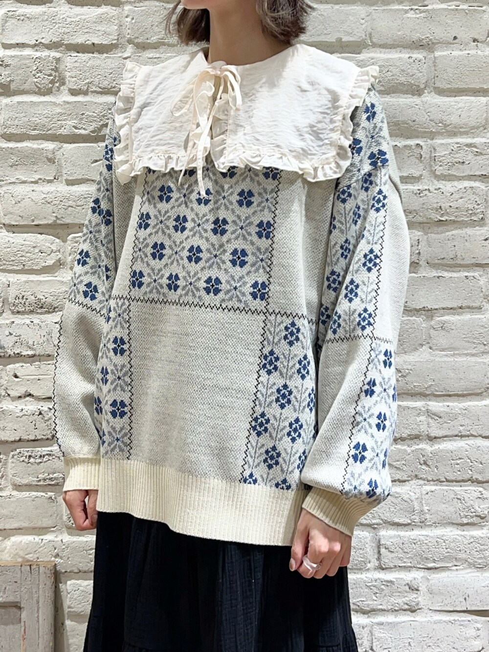 ホワイト系のシャツ/ブラウス、ホワイト系のニット/セーター、ブラック系のスカートを着用したレディースの冬コーディネートの2枚目の写真