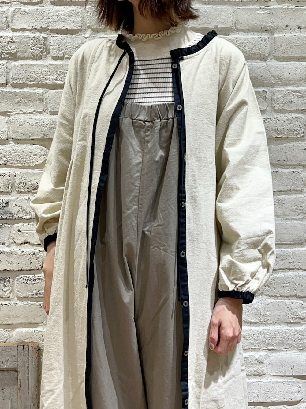 ホワイト系のニット/セーター、ブラウン系のサロペット/オーバーオール、ブラック系のサンダルを着用したレディースの冬コーディネートの2枚目の写真