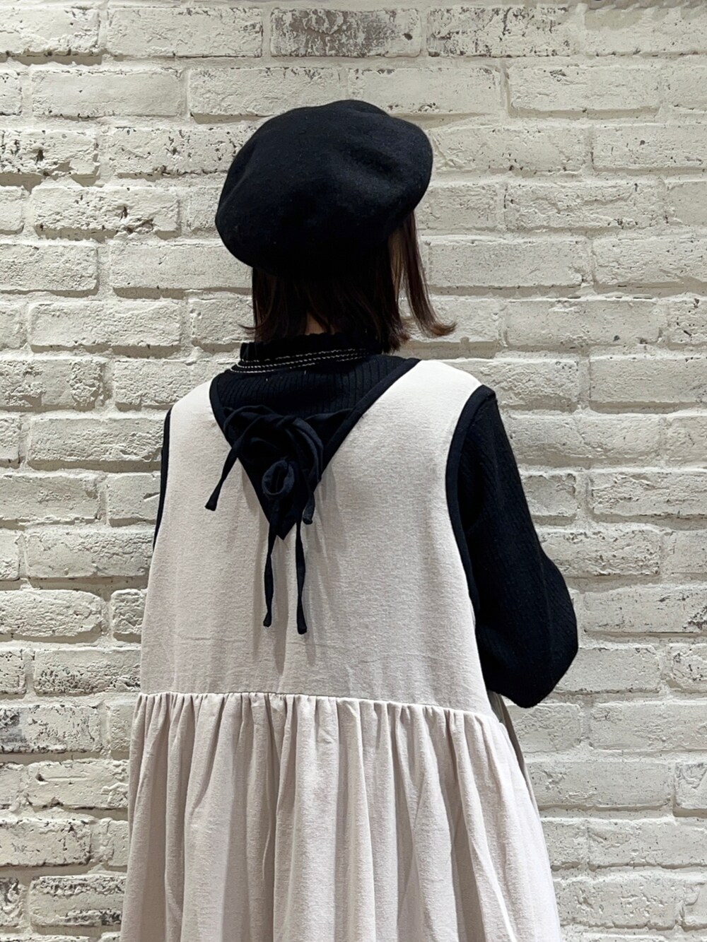 ブラック系のニット/セーター、ホワイト系のワンピース、ベージュ系のスカートを着用したレディースの冬コーディネートの4枚目の写真