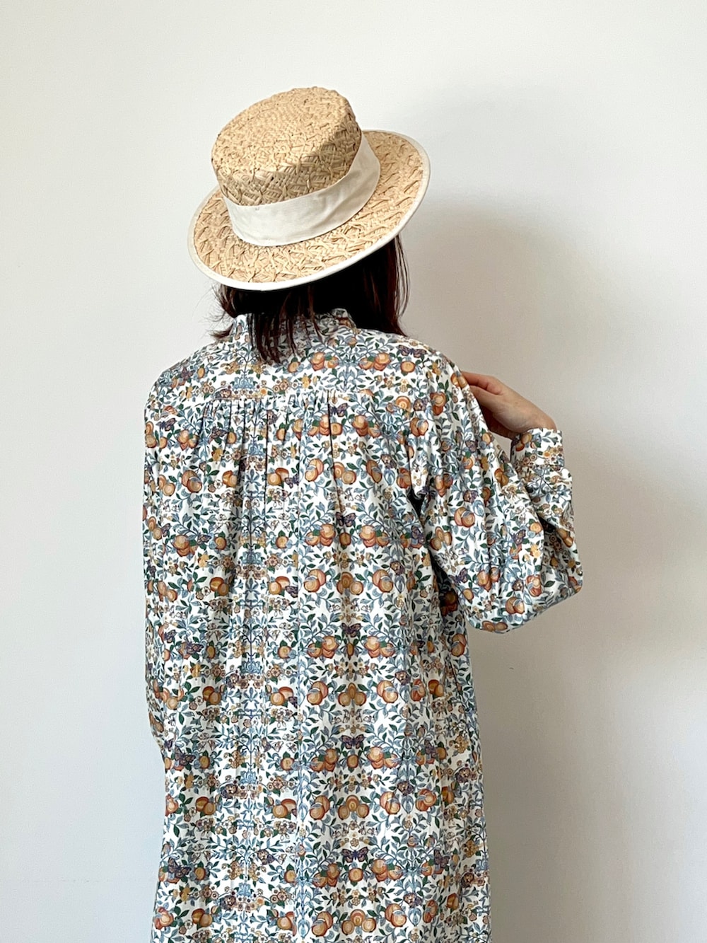 オレンジ系のワンピース、ホワイト系のサンダル、ホワイト系のハットを着用したレディースの春コーディネートの5枚目の写真