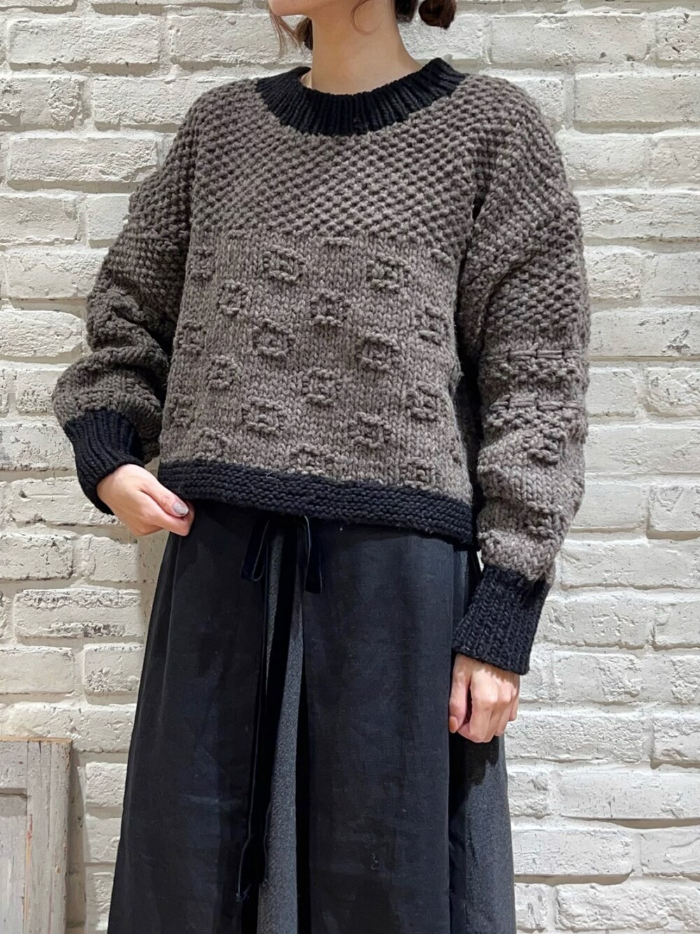 ブラウン系のニット/セーター、グレー系のスカート、ブラウン系のストール/ショールを着用したレディースの冬コーディネートの2枚目の写真