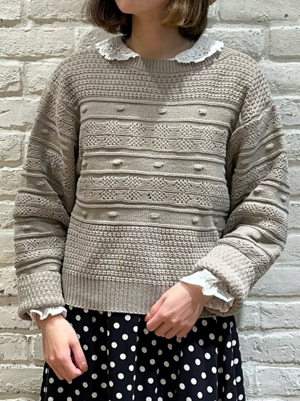 ベージュ系のニット/セーター、ホワイト系のシャツ/ブラウス、ブラック系のスカートを着用したレディースの冬コーディネートの2枚目の写真