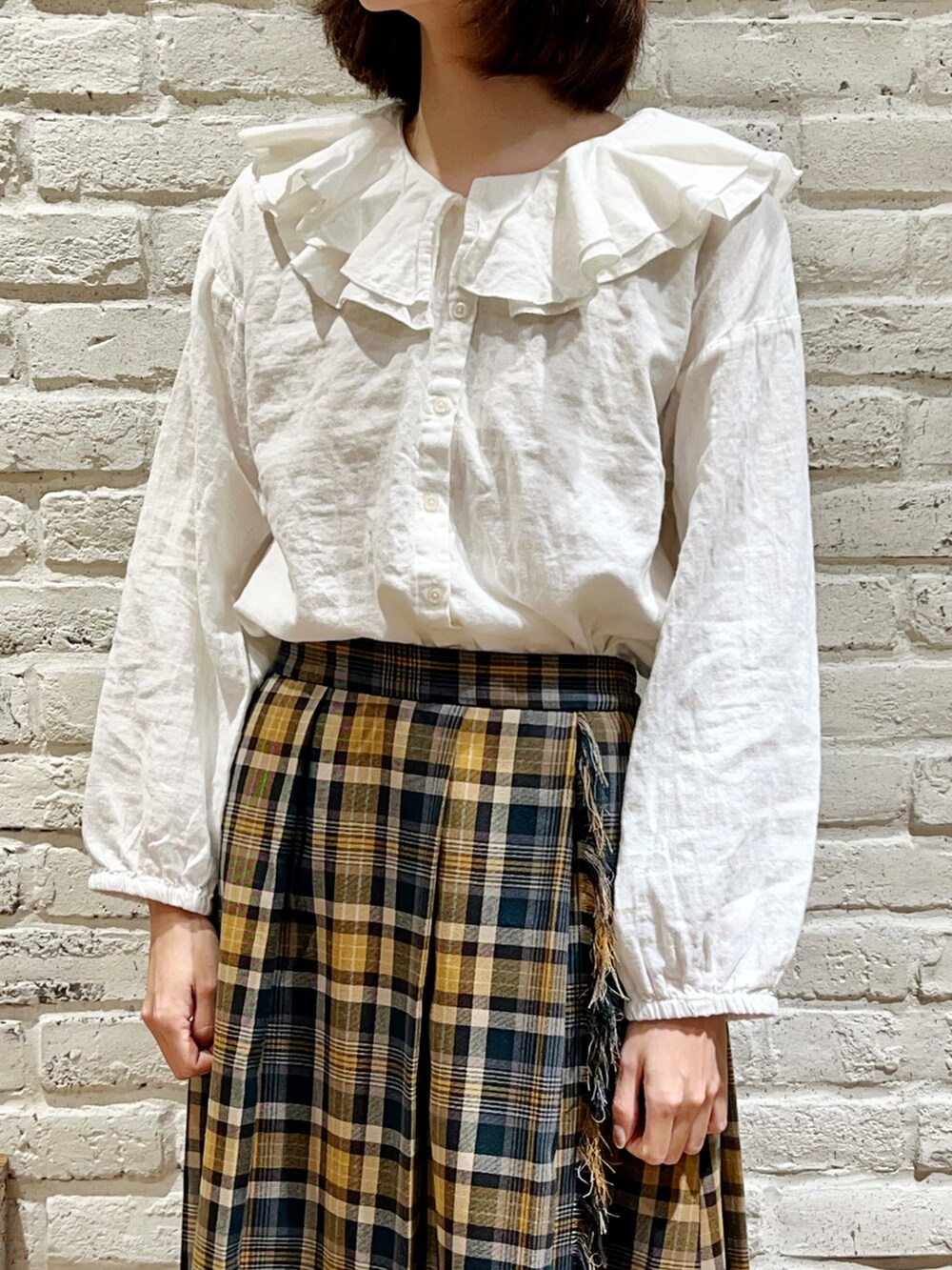 ホワイト系のシャツ/ブラウス、オレンジ系のカーディガン/ボレロ、グリーン系のスカートを着用したレディースの冬コーディネートの3枚目の写真