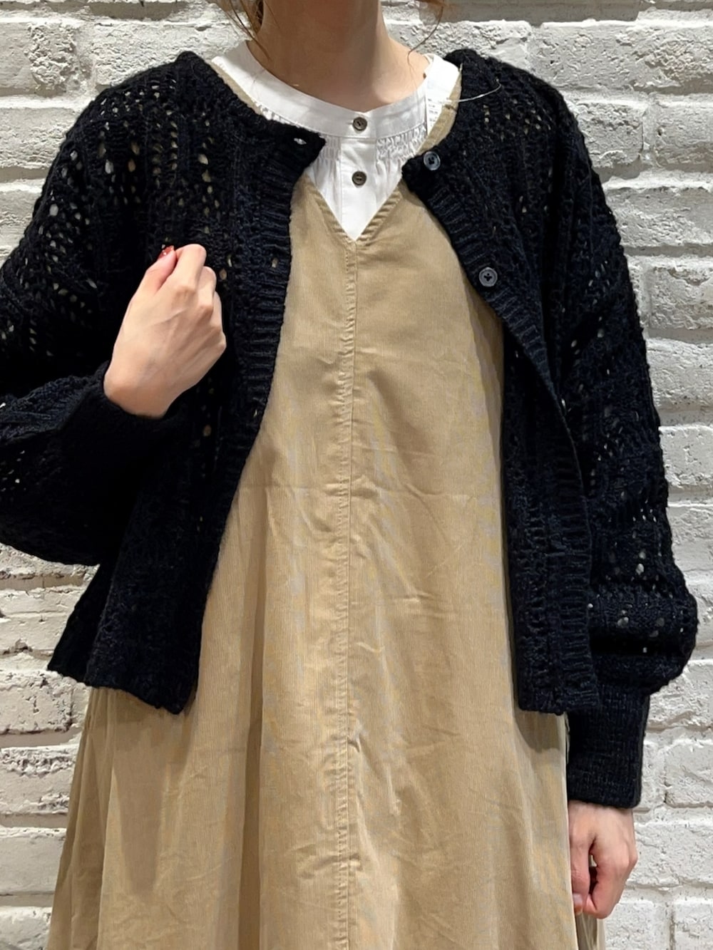 ホワイト系のシャツ/ブラウス、ブラック系のカーディガン/ボレロ、ベージュ系のジャンパースカートを着用したレディースの秋コーディネートの2枚目の写真