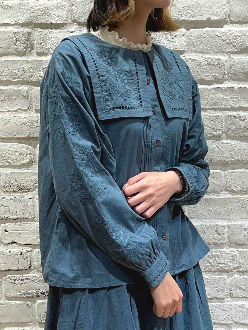 ホワイト系のTシャツ/カットソー、グリーン系のシャツ/ブラウス、ベージュ系のノーカラーコートを着用したレディースの秋コーディネートの3枚目の写真