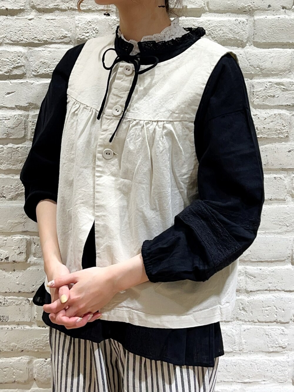 グリーン系のステンカラーコート、ホワイト系のベスト、ブラック系のシャツ/ブラウスを着用したレディースの春コーディネートの3枚目の写真