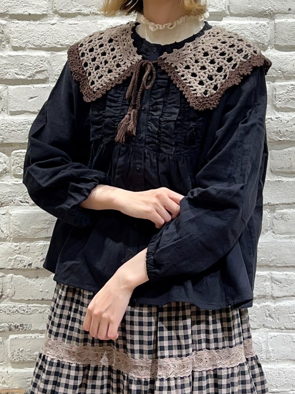 ホワイト系のニット/セーター、ブラック系のシャツ/ブラウス、ブラウン系のハンドバッグを着用したレディースの秋コーディネートの2枚目の写真