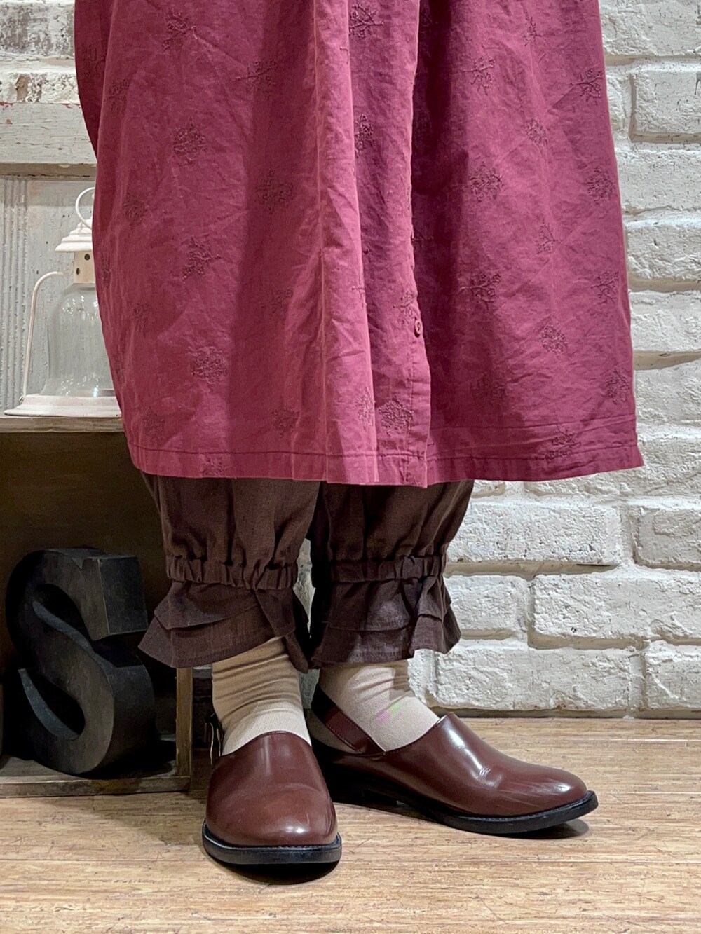 ベージュ系のベスト、レッド系のワンピース、グレー系のその他パンツを着用したレディースの秋コーディネートの5枚目の写真