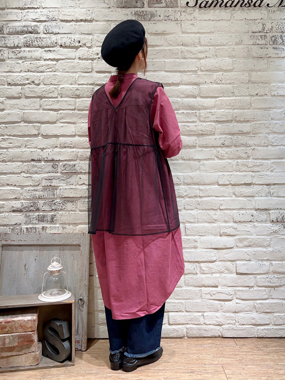 パープル系のワンピース、ブラック系のベスト、ブルー系のデニムパンツを着用したレディースの秋コーディネートの4枚目の写真