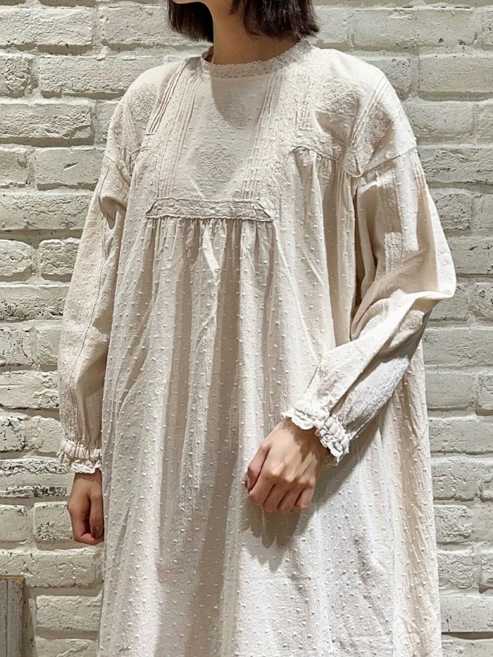 ホワイト系のワンピース、ベージュ系のスカート、ブラウン系のドレスシューズを着用したレディースの冬コーディネートの2枚目の写真