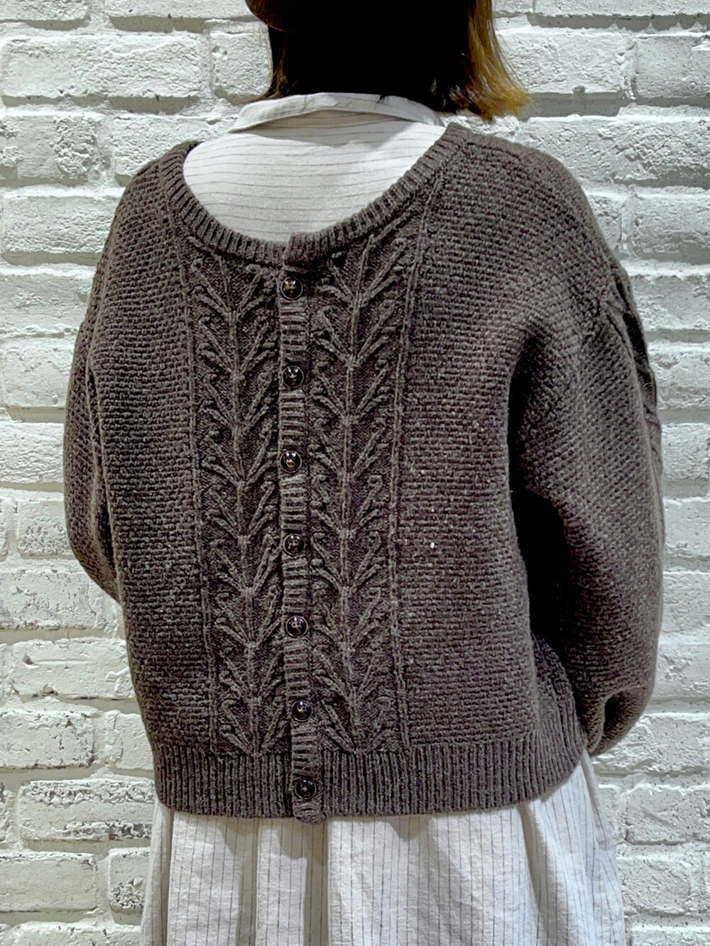 ブラウン系のカーディガン/ボレロ、ベージュ系のワンピース、ブラック系のスカートを着用したレディースの秋コーディネートの5枚目の写真