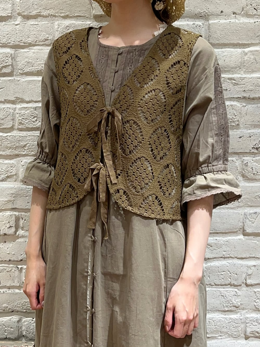 グリーン系のベスト、グリーン系のワンピース、ホワイト系のスカートを着用したレディースの秋コーディネートの2枚目の写真