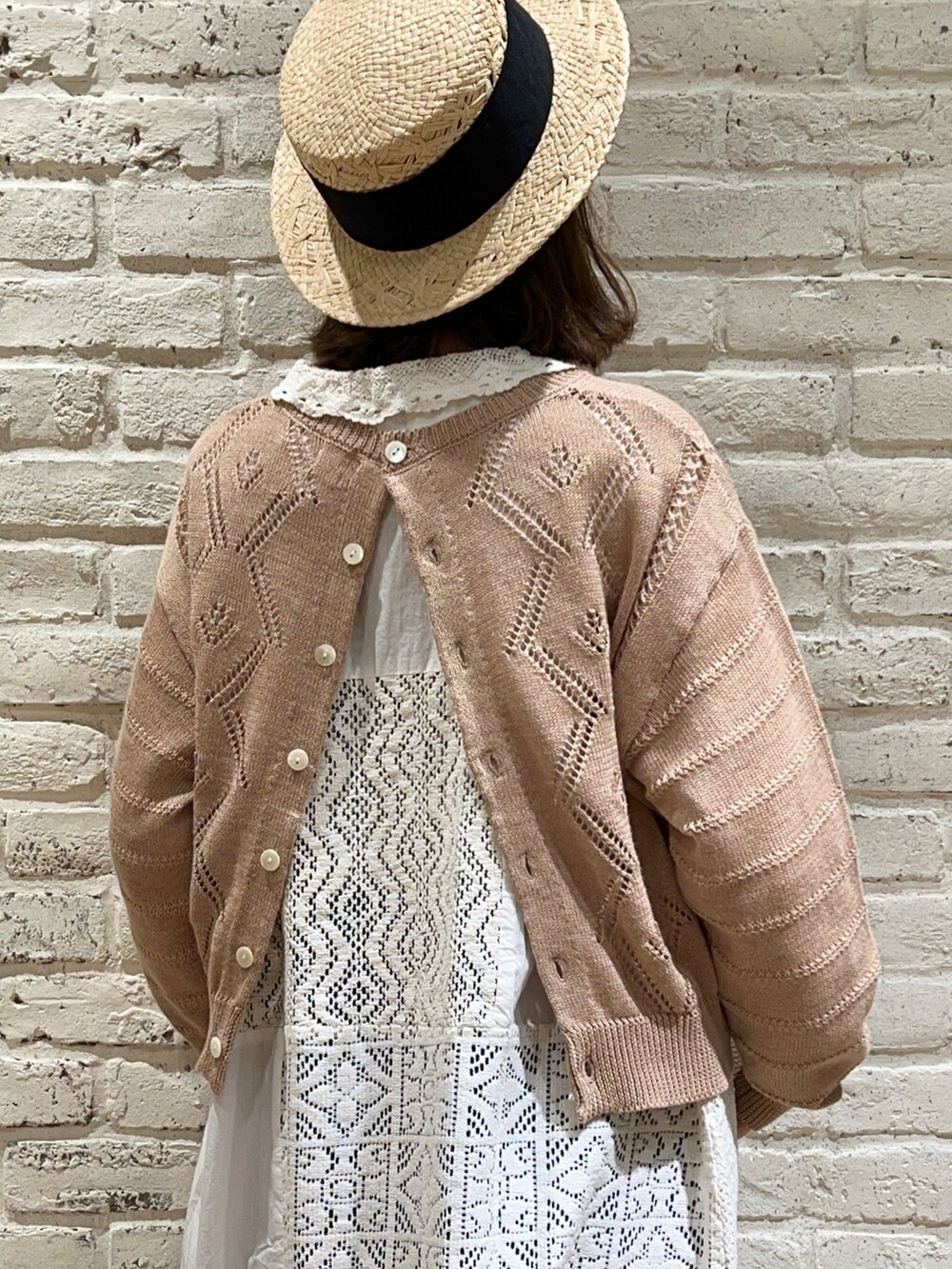 ブラウン系のニット/セーター、ホワイト系のワンピース、ブルー系のデニムパンツを着用したレディースの春コーディネートの5枚目の写真