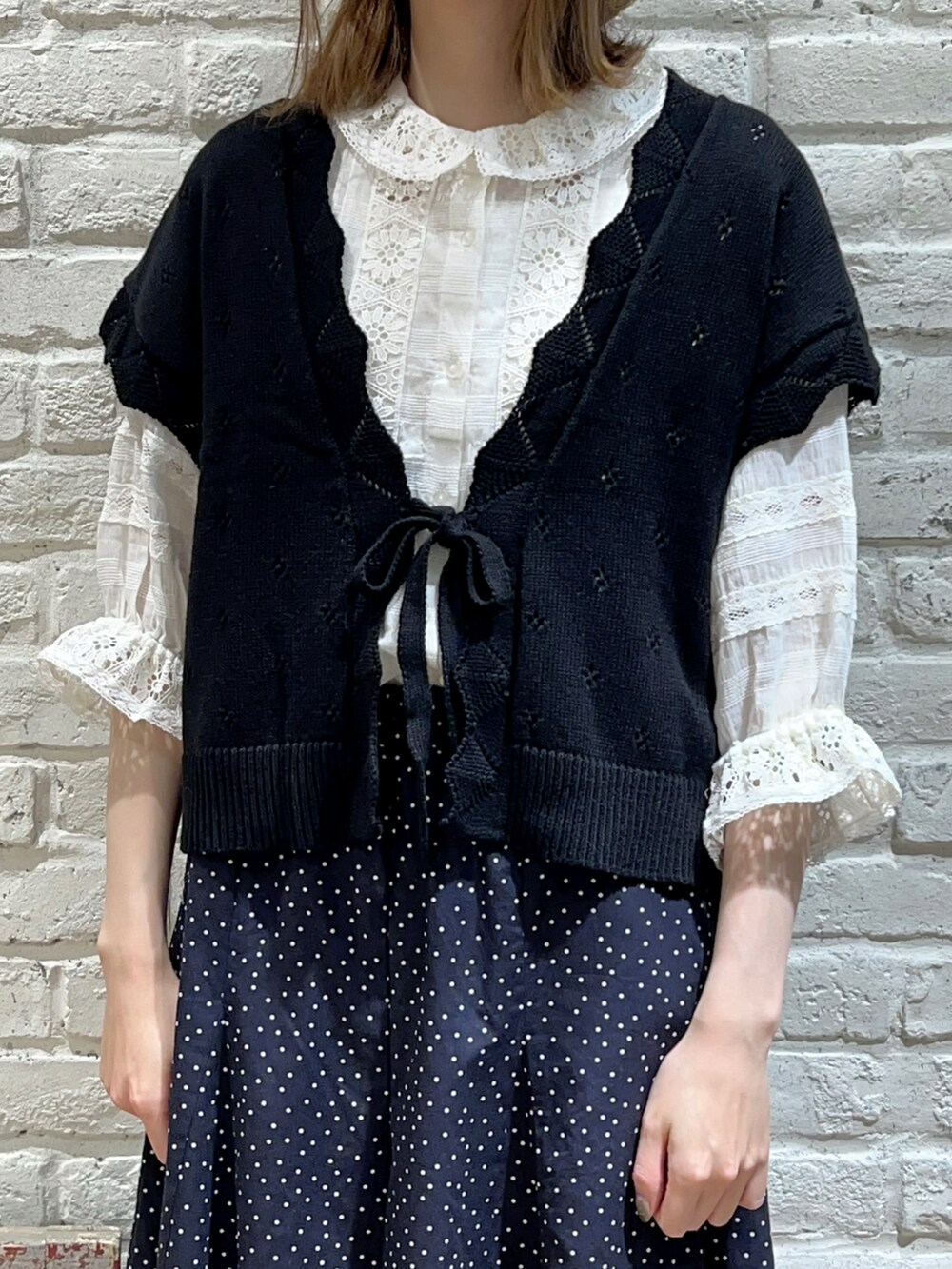 ホワイト系のシャツ/ブラウス、ブラック系のベスト、ホワイト系のハンドバッグを着用したレディースの春コーディネートの2枚目の写真