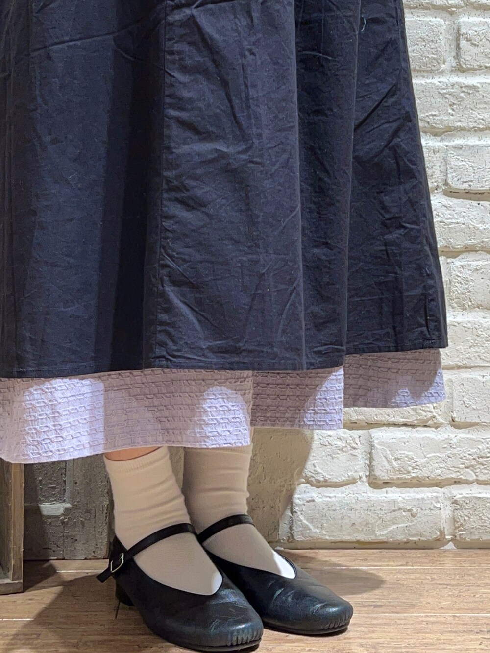 ホワイト系のカーディガン/ボレロ、ブラック系のワンピース、パープル系のスカートを着用したレディースの冬コーディネートの5枚目の写真