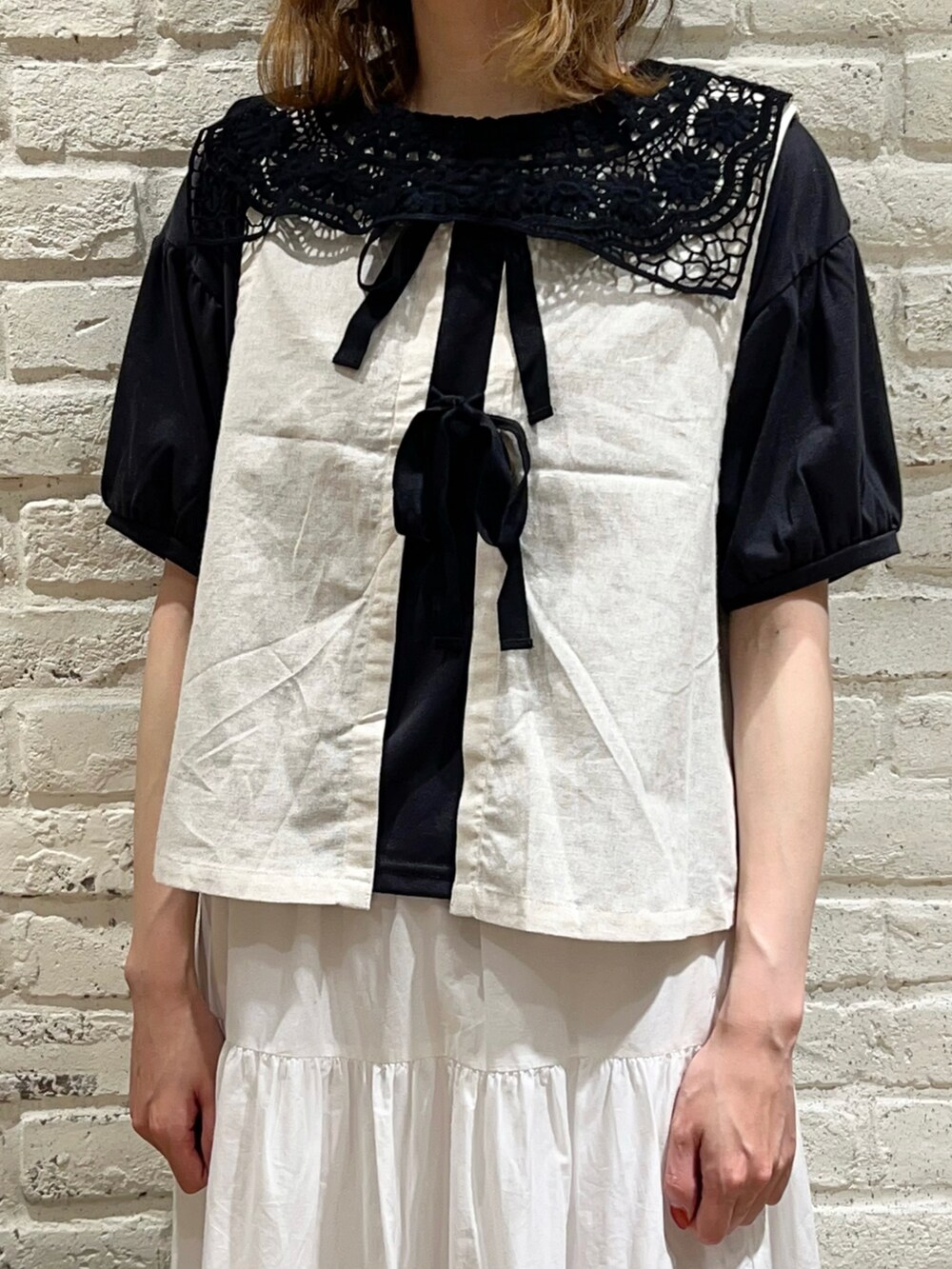 グレー系のTシャツ/カットソー、ホワイト系のベスト、ブラック系のスカートを着用したレディースの秋コーディネートの4枚目の写真