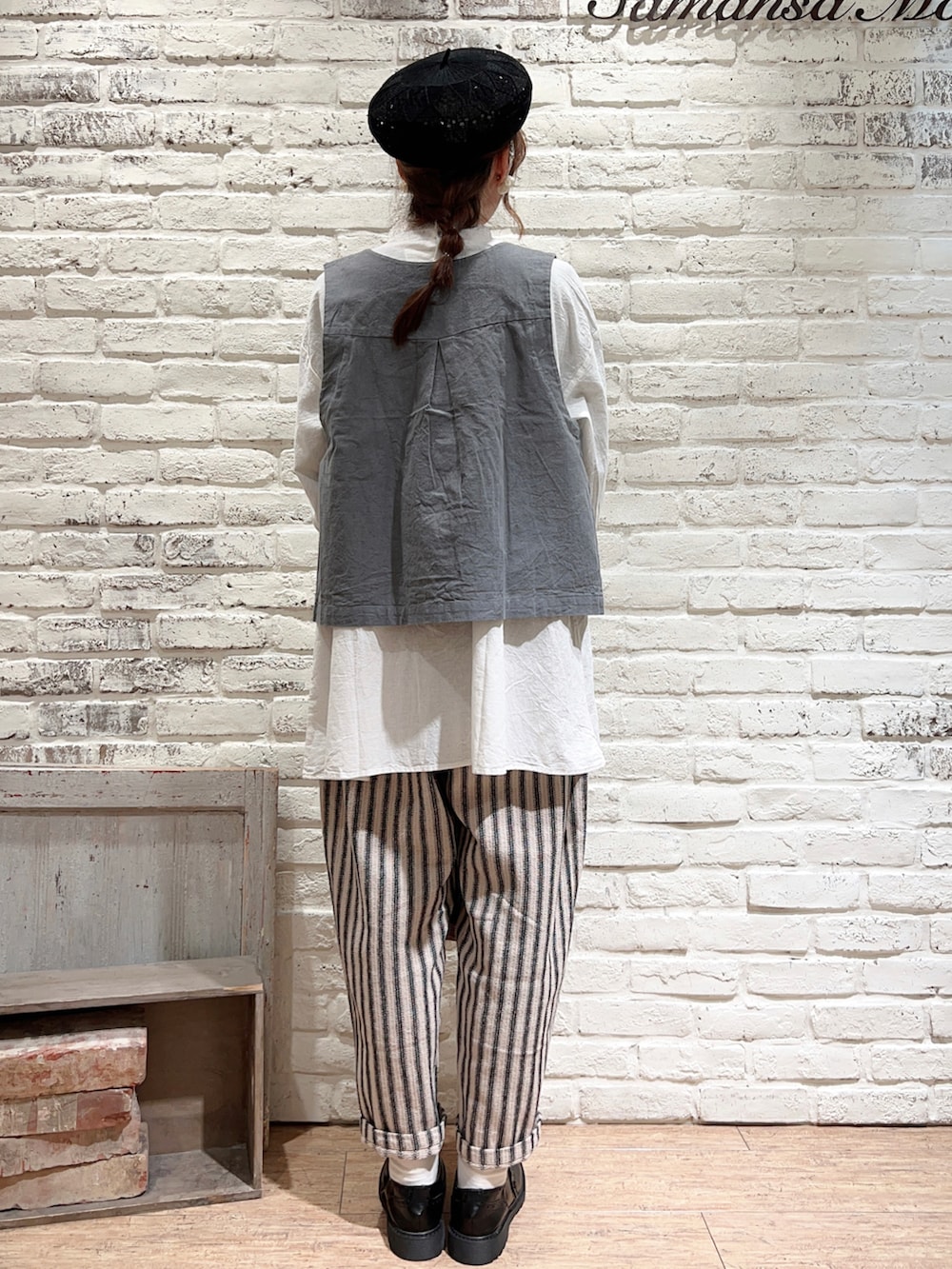 グリーン系のベスト、ホワイト系のシャツ/ブラウス、ブラック系のかごバッグを着用したレディースの春コーディネートの4枚目の写真