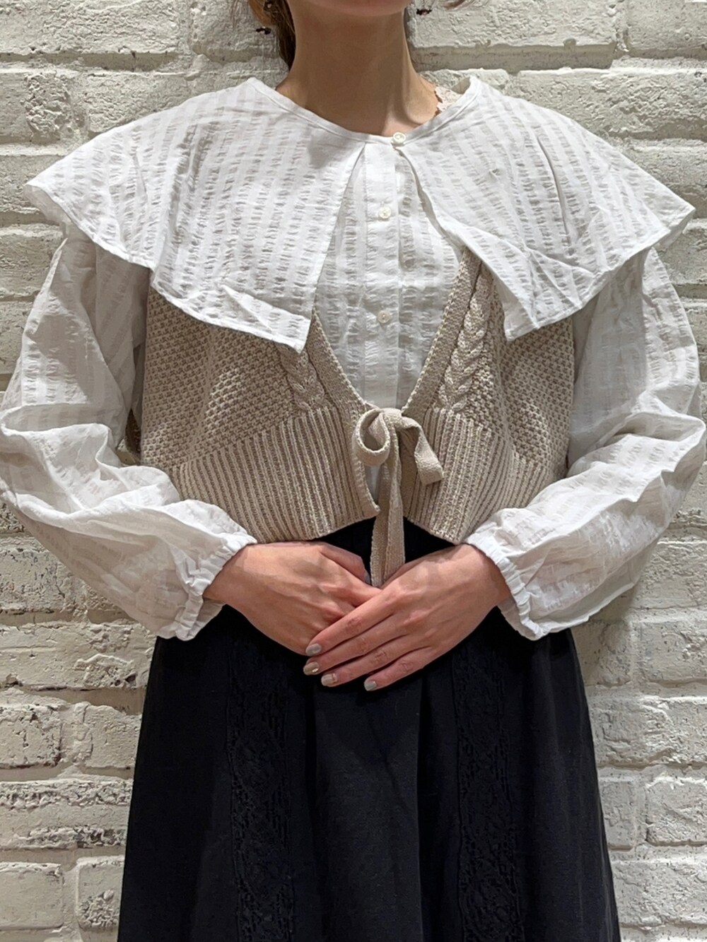 ベージュ系のTシャツ/カットソー、ホワイト系のシャツ/ブラウス、ベージュ系のニット/セーターを着用したレディースの冬コーディネートの2枚目の写真