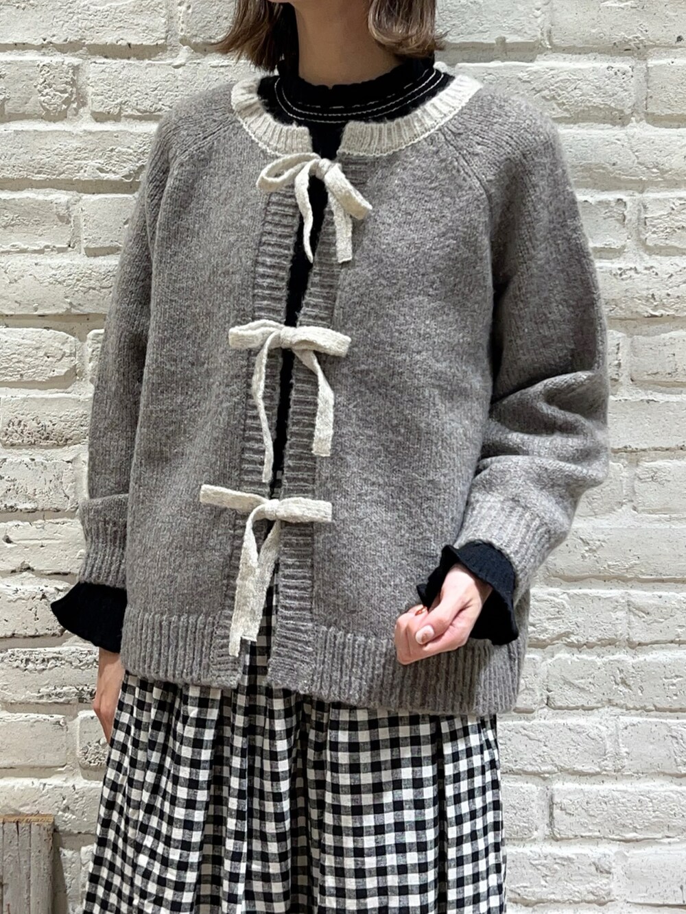 ブラック系のニット/セーター、ベージュ系のカーディガン/ボレロ、ベージュ系のスカートを着用したレディースの冬コーディネートの2枚目の写真