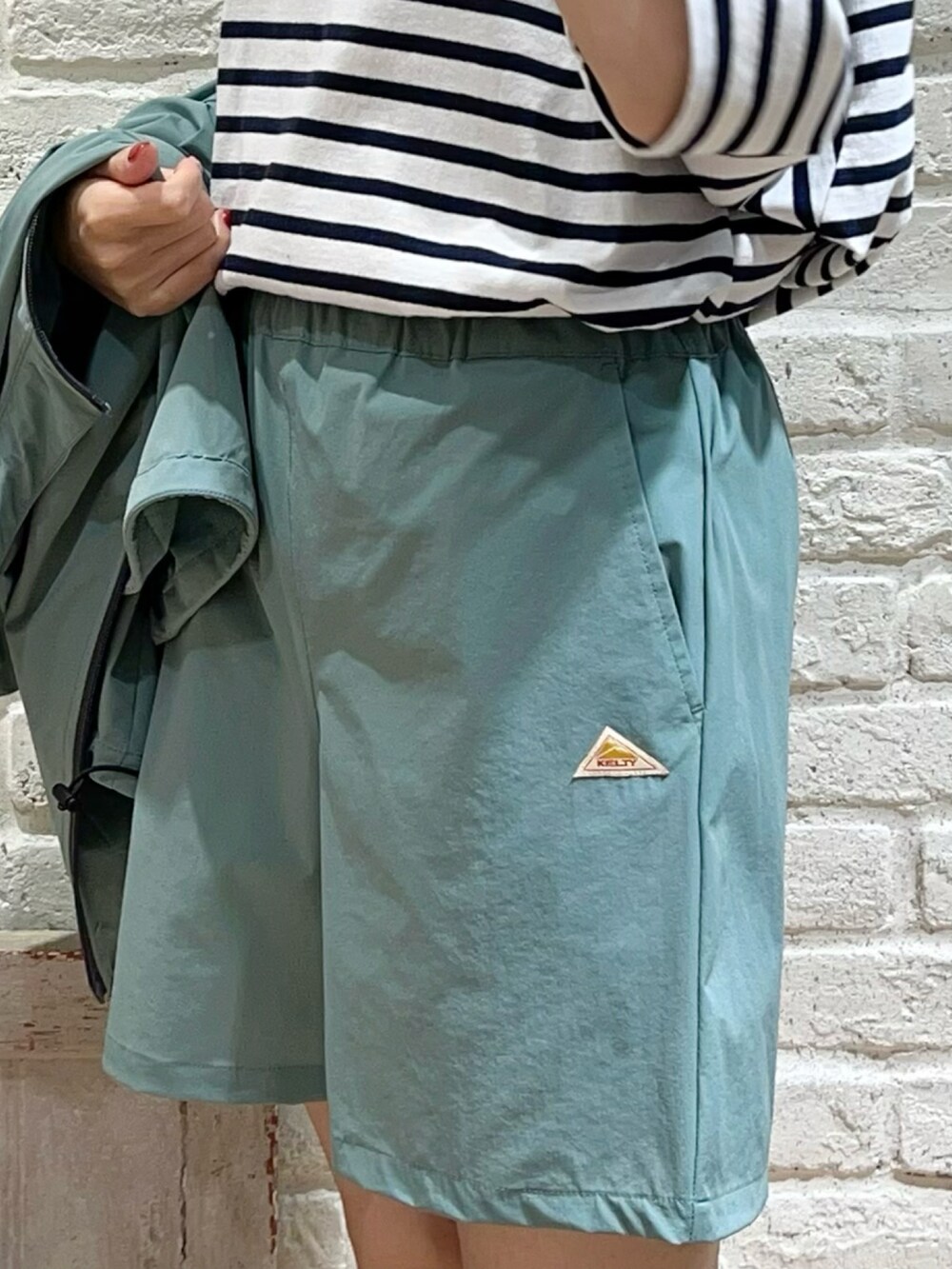 ホワイト系のタンクトップ、ホワイト系のTシャツ/カットソー、グリーン系のブルゾンを着用したレディースの春コーディネートの3枚目の写真