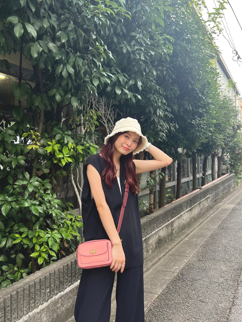 ピンク系のショルダーバッグ、ブラック系のベスト、ブラック系のその他パンツを着用したレディースの夏コーディネートの2枚目の写真