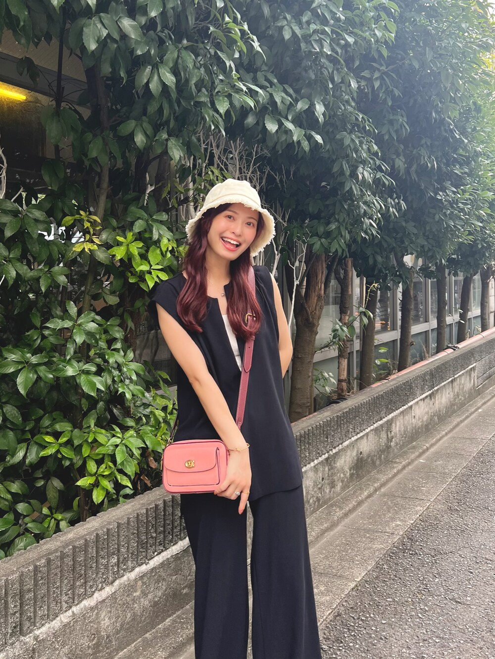 ピンク系のショルダーバッグ、ブラック系のベスト、ブラック系のその他パンツを着用したレディースの夏コーディネートの4枚目の写真